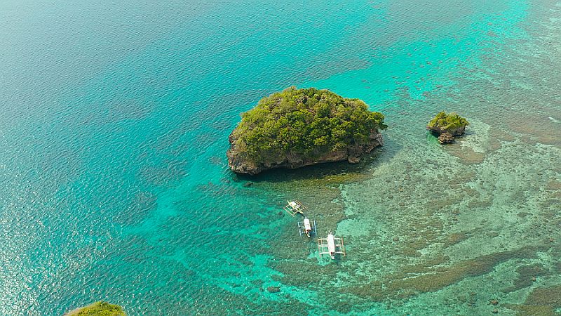 Clear turquoise water in a lagoon with rocky islands and corall reef from above Boracay, 